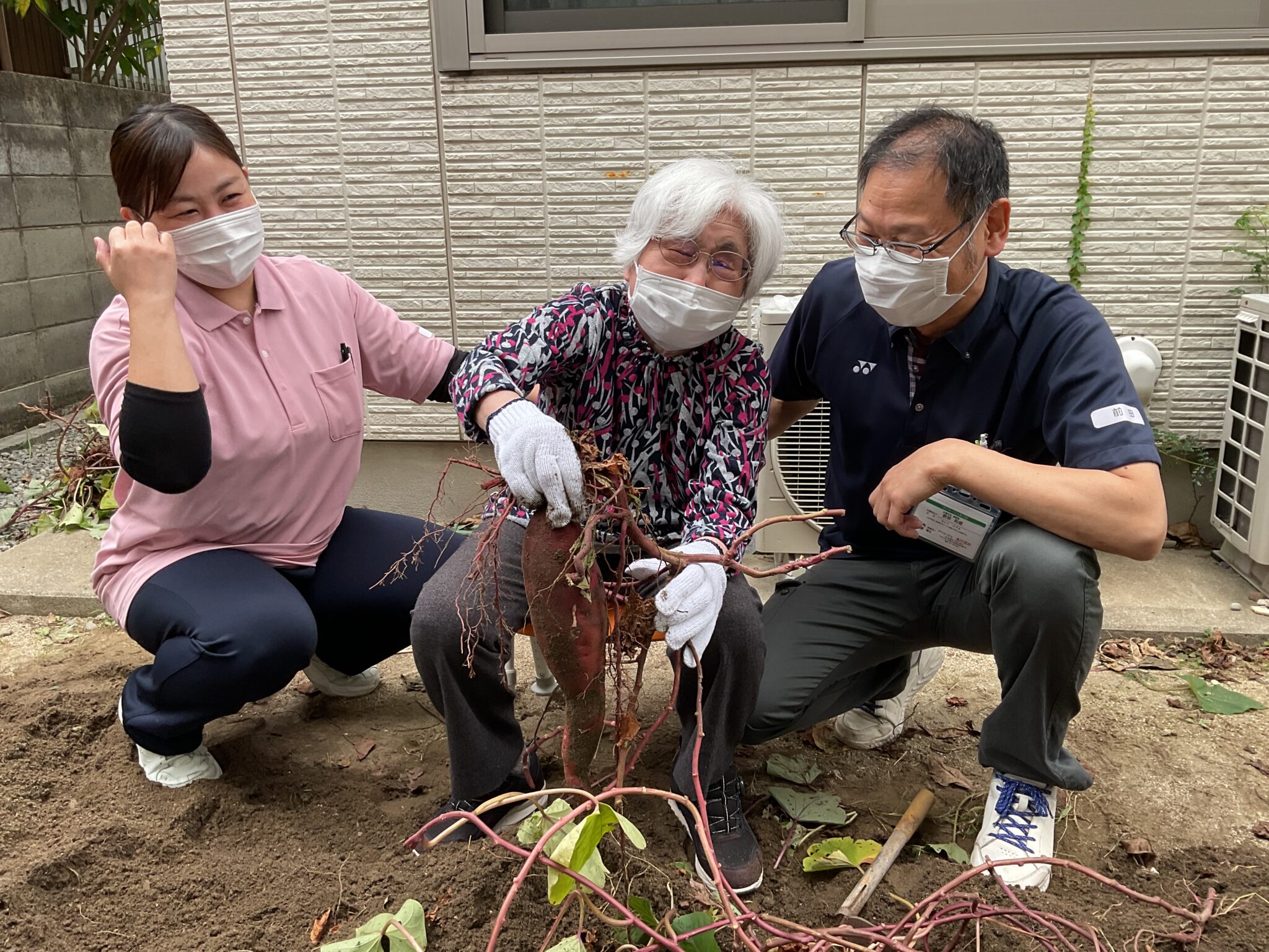 入居者と職員が一緒に庭で植物を育てる生活風景